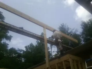 Carpenter setting a ridge beam over a new addition frame — Ice Dam Removal by Roofing Brothers in Clarkson
