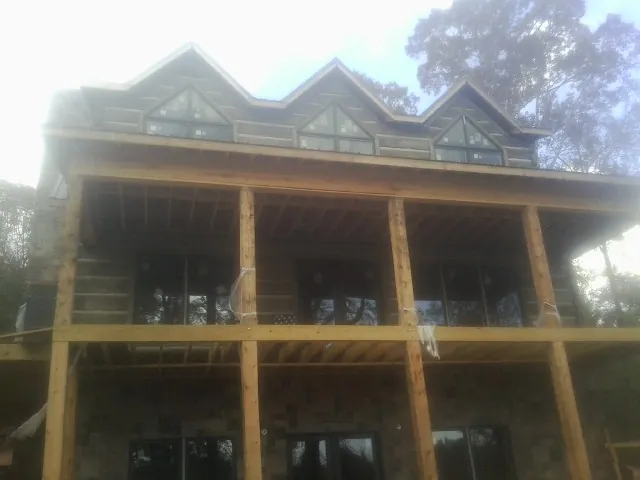 Dormers and porch framing on a large log home under construction — Roof Coating work by our crew in Clarkson