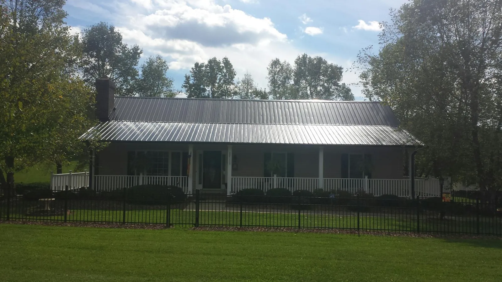 Gray metal roof on a brick ranch with a full width front porch — Gutter Guard Installation work by our crew in Clarkson